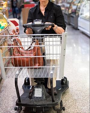 Elderly woman in grocery store driving a motorized shopping cart scooter that has the capability of causing serious injury if not handled correctly