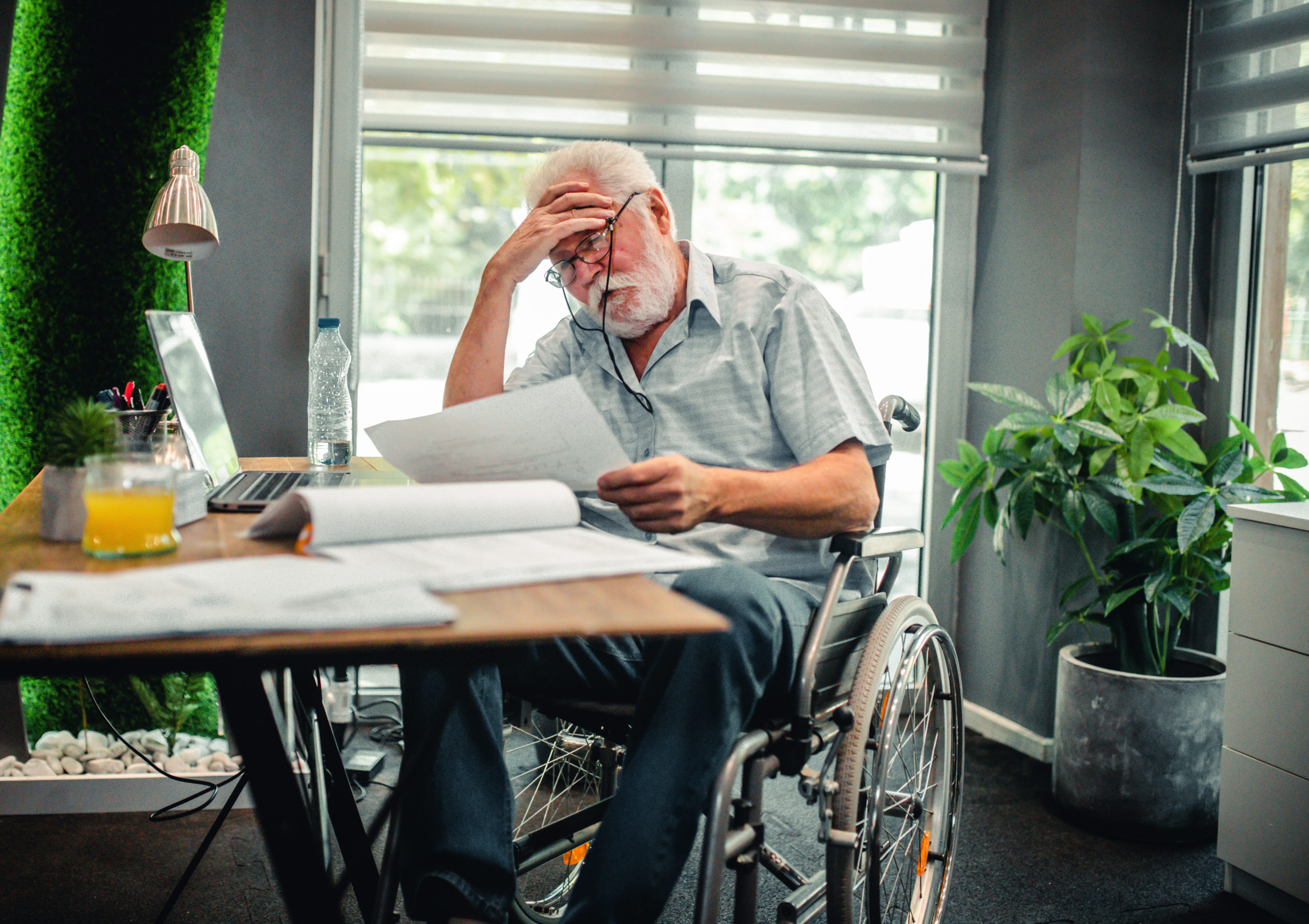 Disabled senior man in a wheelchair in a office