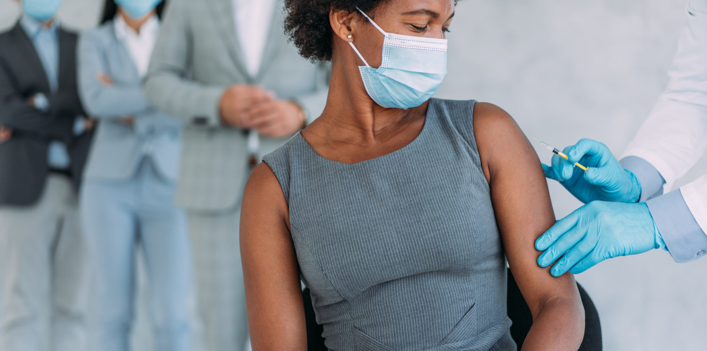 Young businesswoman getting vaccinated in the office.