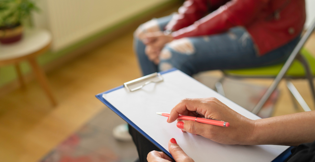 Close up of a female psychologist taking notes and a students knees