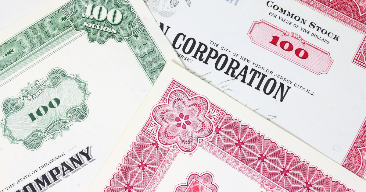Three Corporate Stock Certificates Lying Atop Each Other At Angles, Some Printed In Red Ink And Blank Ink, Some Printed In Green Ink and Black Ink