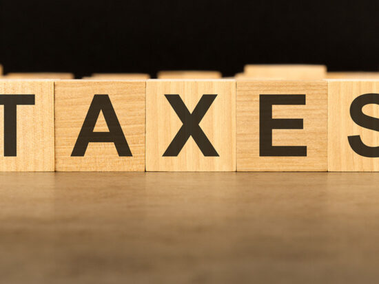 word TAXES written on wooden cube block stack on black background, business concept