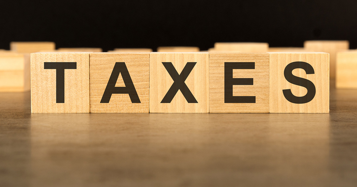word TAXES written on wooden cube block stack on black background, business concept