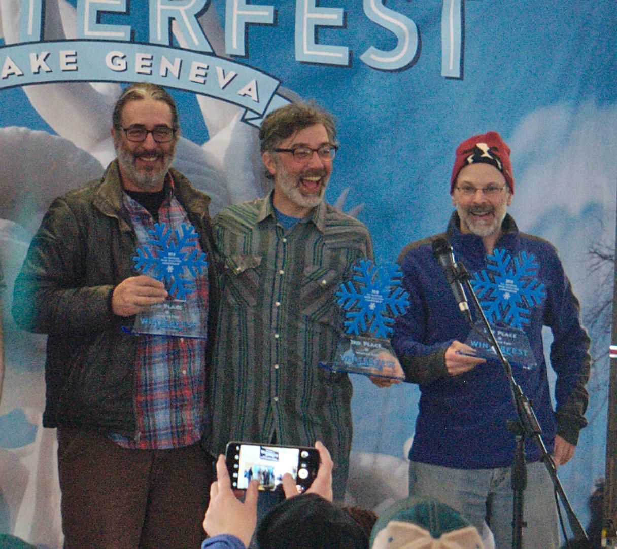 Winning snow sculpture team smiling and holding up their awards.