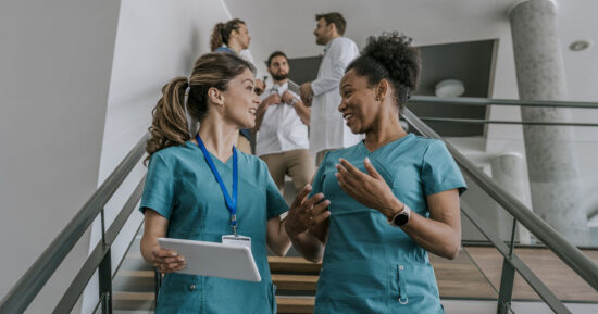 Two female doctors chatting while walking upstairs in a hospital