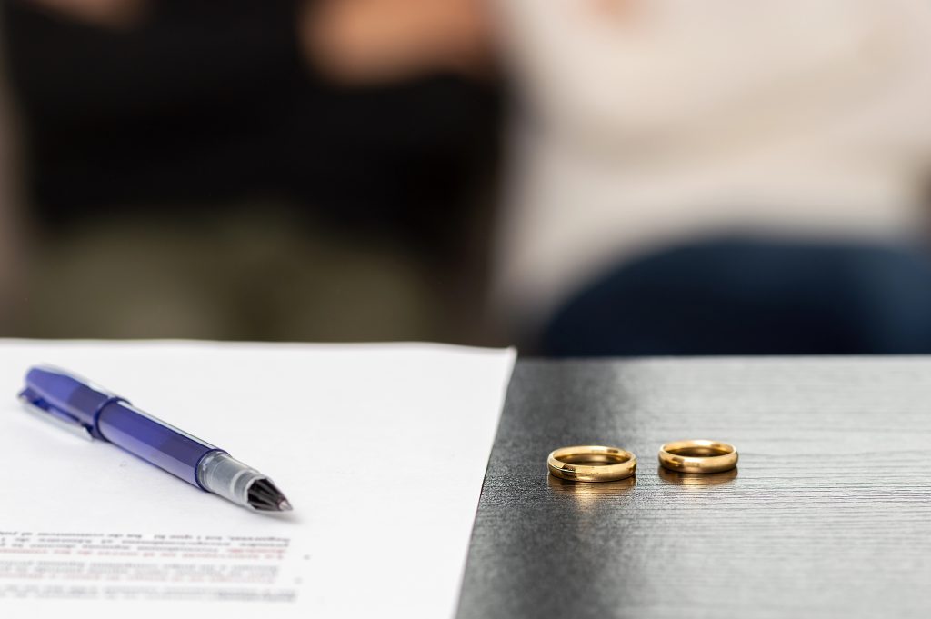 Wedding rings set next to divorce papers.